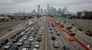 Heavy traffic congestion on the Stemmons Freeway I-35E corridor near downtown Dallas with visible construction barriers and lane closures 